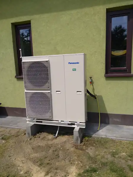 Jednostka zewnętrzna pompy ciepła Panasonic Aquarea zamontowana na podstawie przy elewacji domu jednorodzinnego